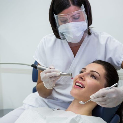 Dentist examining a female patient with tools at dental clinic